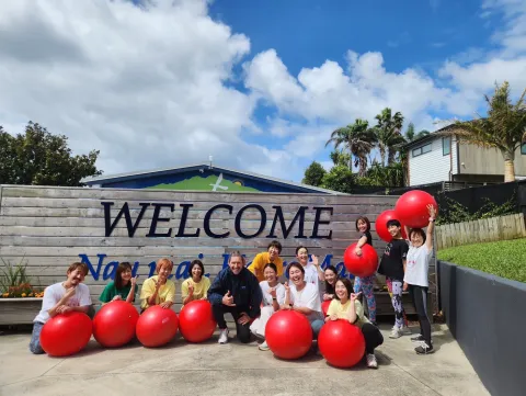 2025年 ニュージーランド 海外研修 Mairangi Bay School の前でバランスボールを持った集合写真